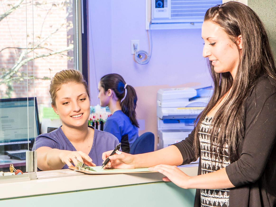 A health unit clerk at a dental office helps client